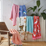 A group of colorful Masai Mara beach towels hanging on a wooden fence in Kenya, by John Robshaw. - 4128606748718