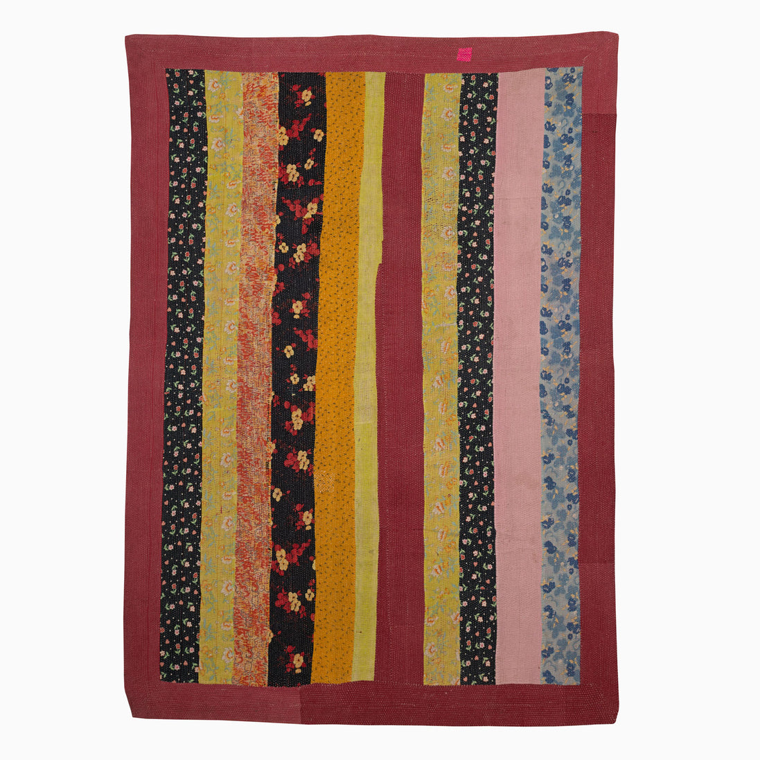 A John Robshaw Sit Up Please quilt hanging on a wall in India.