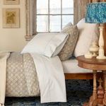 A John Robshaw Cinde Light Indigo Organic Sheet Set made of 100% cotton percale with a lamp on top of it. - 30264085741614