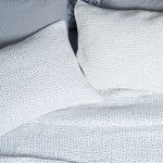 A bed with John Robshaw Organic Hand Stitched Light Indigo Quilt coverlets and blue and white polka dot pillows. - 28362848698414