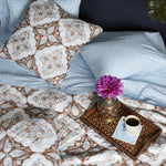 A bed with Kama Light Indigo Organic Sheet Set bedding by John Robshaw and a tray with a cup of coffee. - 28362869538862