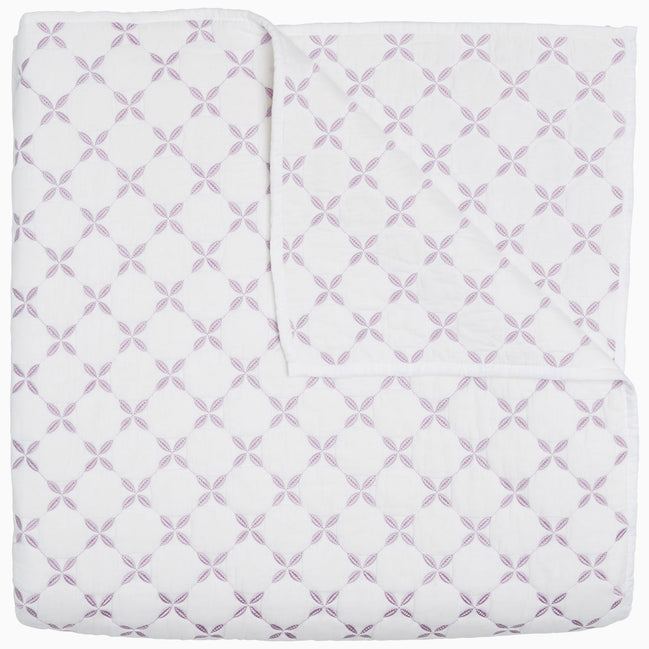 A Layla Lavender quilt by John Robshaw, made from cotton voile, with a cross pattern in white and purple, inspired by Mughal gardens.