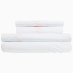 A stack of Stitched Blush Organic Sheets by John Robshaw with pink piping and embroidered designs. - 28765998579758