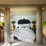 A bedroom with a Layla Indigo Quilt by John Robshaw dressed in soft cotton voile sheets, accompanied by a stylish bedside table. - 28783182676014