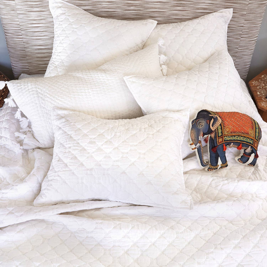 A white bed with pillows and a John Robshaw Layla White Quilt.