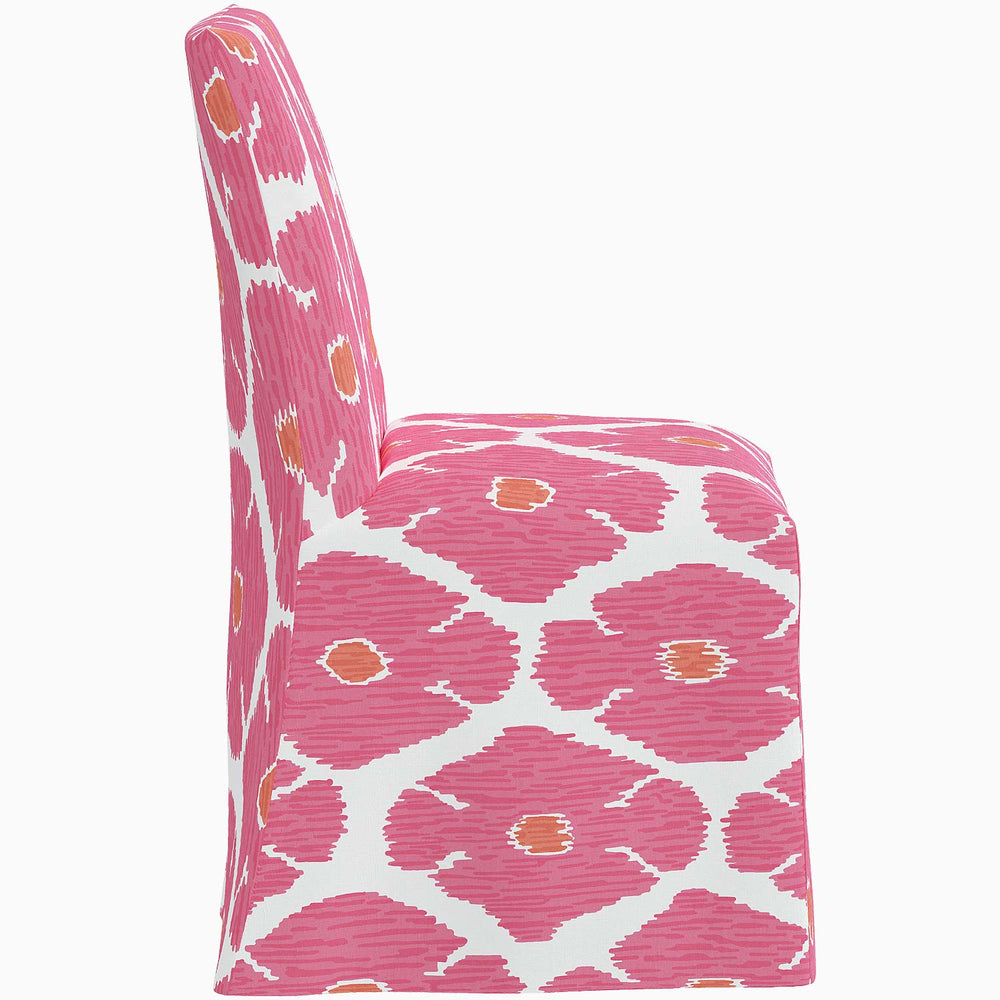 The John Robshaw Sadia Slipcover Chair is a pink and white dining chair with a floral pattern.