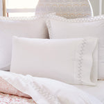 A bed with John Robshaw's Stitched Gray Organic Sheets prints and embroidered designs on a white comforter and pillows. - 30273371570222