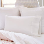 A John Robshaw white bed with the Stitched White Organic Sheets featuring embroidered designs. - 30273372717102