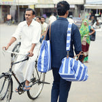 A man on a bicycle carrying a John Robshaw Vintage Stripe Tote Bag. - 6601740648494