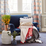 A hand stitched blue chair with a pile of John Robshaw Sahati Indigo Throw blankets in front of a window. - 11324224634926