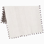 A Sahati Charcoal Throw by John Robshaw, a cotton knitted rug with tassels, that is machine washable. - 28455932788782