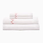 A stack of Stitched Coral Organic Sheets with embroidered designs from John Robshaw. - 30252405227566