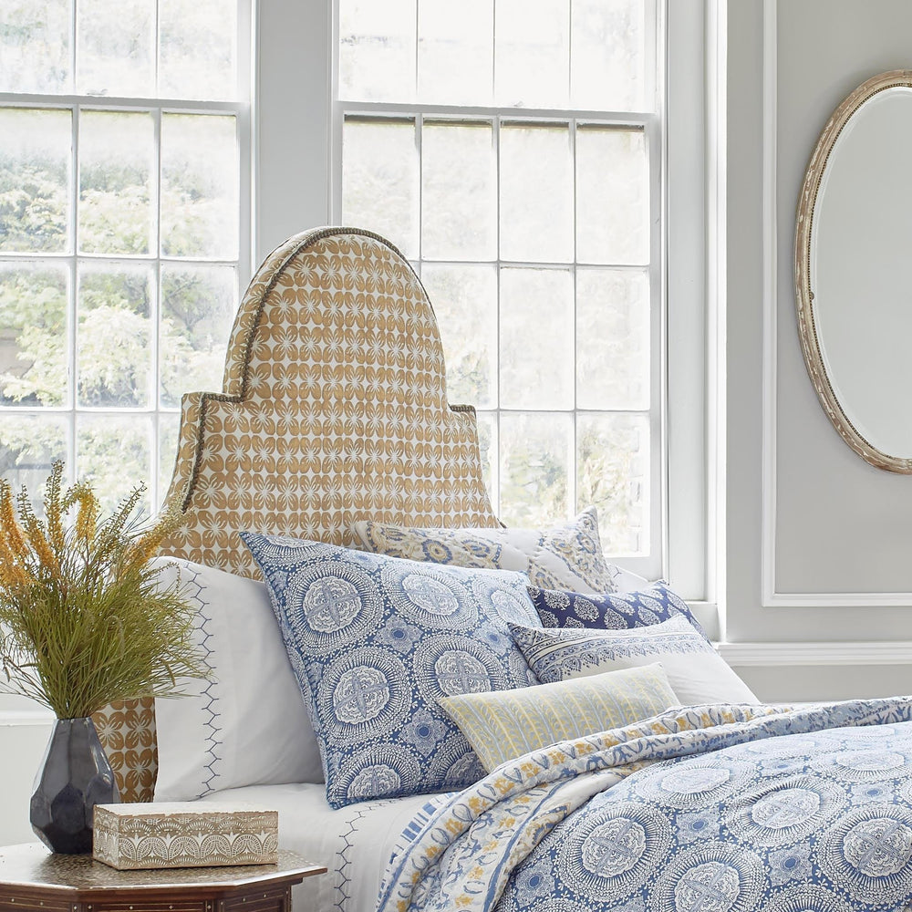 A blue and white bedroom with a John Robshaw Custom Dara Headboard and a mirror available for white glove delivery.