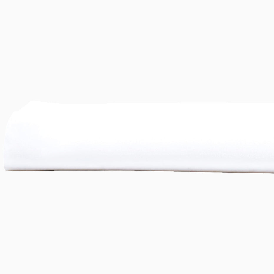 A John Robshaw Organic White Fitted Sheet, made of organic cotton, lying on top of a white surface in India.